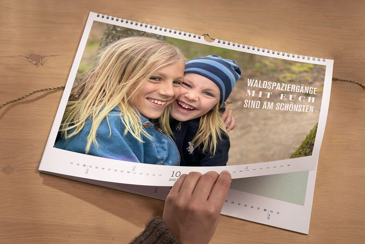 Ein offener Fotokalender zeigt zwei Kinder bei einem Spaziergang. Ein Hand greift nach dem Kalender.