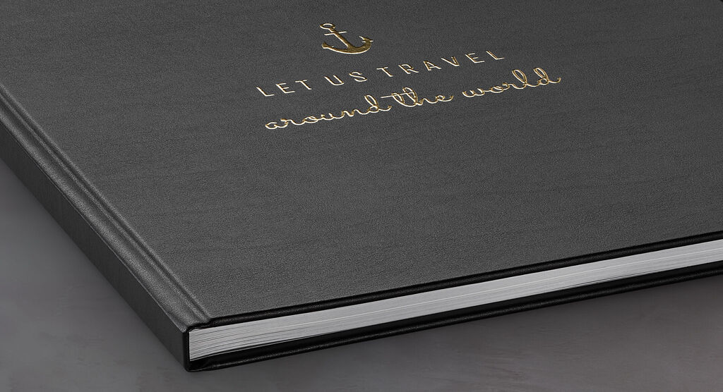 Schwarzes Fotobuch mit goldener Prägung "Let us travel around the world"