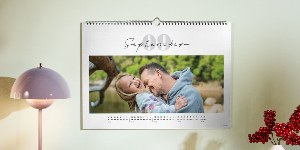 Ein CEWE Fotokalender zeigt Vater und Kind, die sich draußen herzlich umarmen und dabei fröhlich lachen.