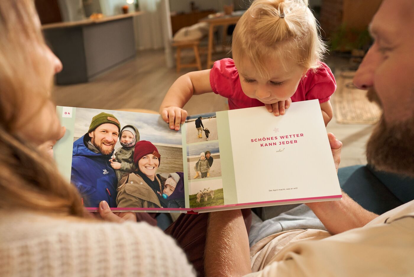 Eltern schauen sich ein CEWE FOTOBUCH an. Ein Mädchen schaut neugierig mit hinein.