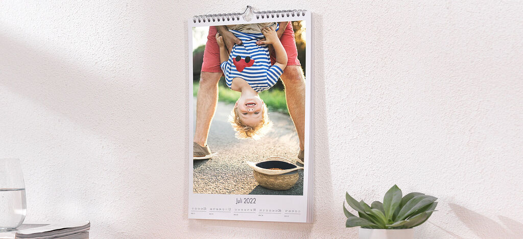 Lebhafter Wandkalender mit einem fröhlichen Jungen, der kopfüber hängt
