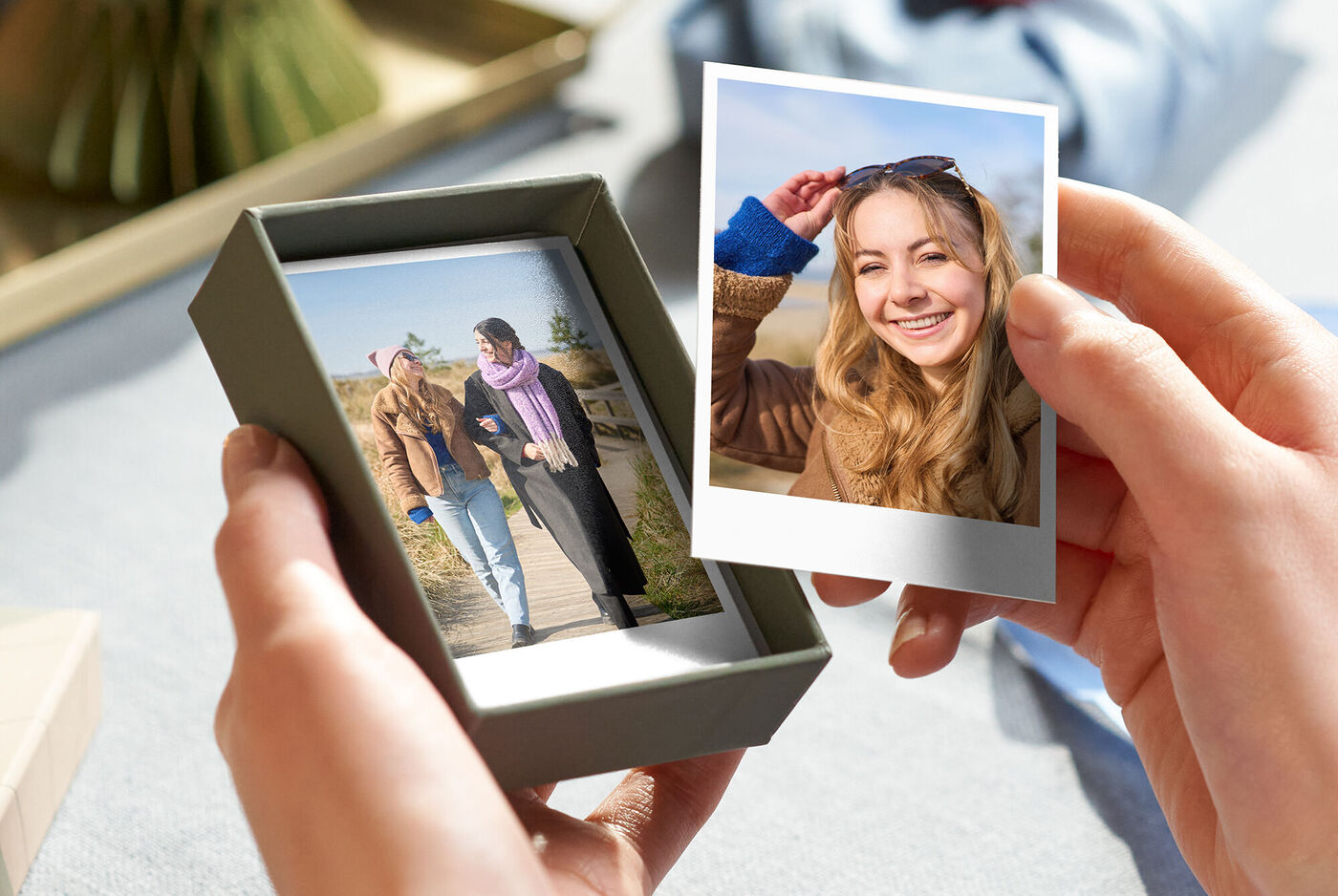 Eine Person hält ein Geschenk mit zwei Fotos in der Hand. Die Bilder zeigen fröhliche Momente.