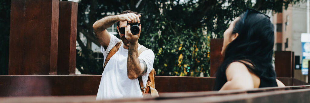 Mann fotografiert Frau in urbaner Umgebung im Sommer.