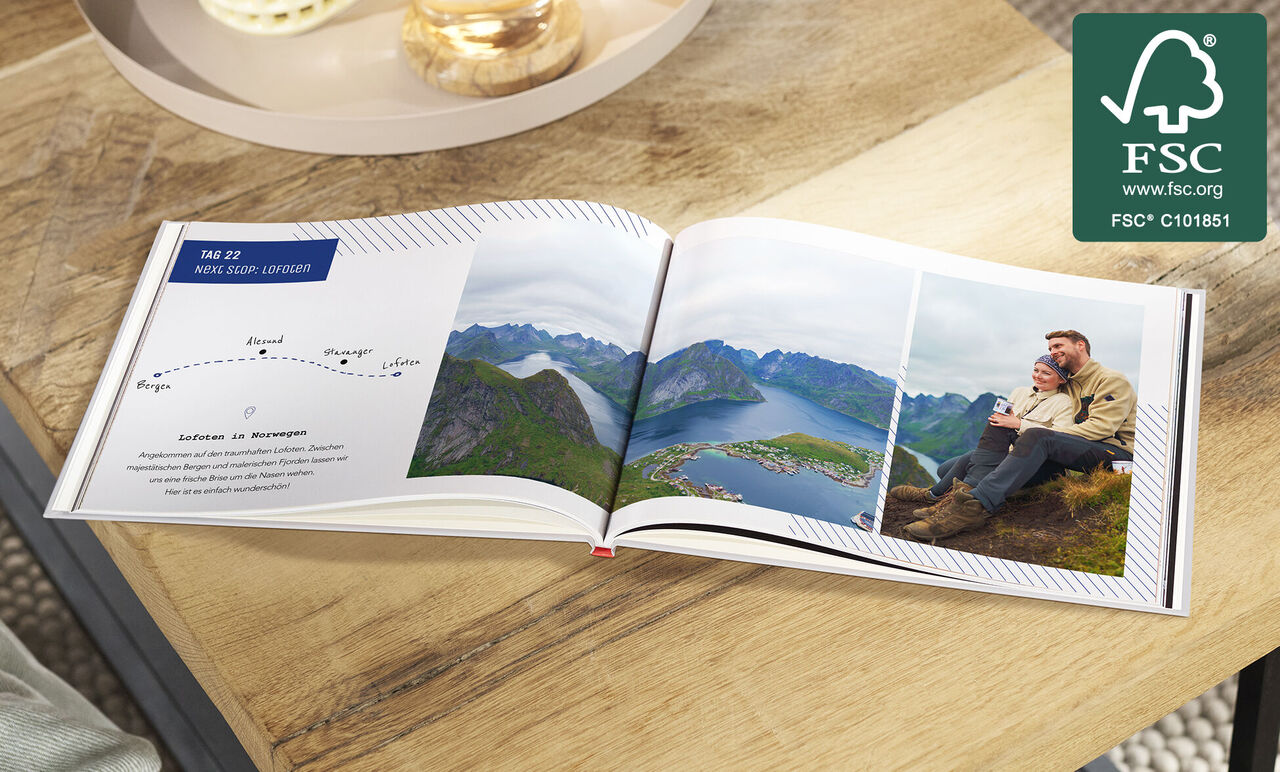Offenes CEWE FOTOBUCH mit Landschaftsfotos und Paar auf Berggipfel