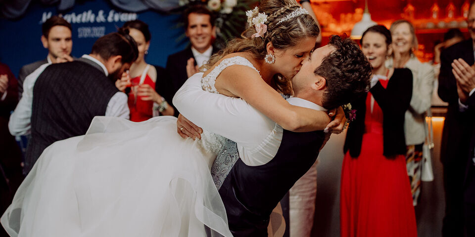 Ein glückliches Paar tanzt liebevoll auf ihrer Hochzeit, umgeben von freudigen Gästen.