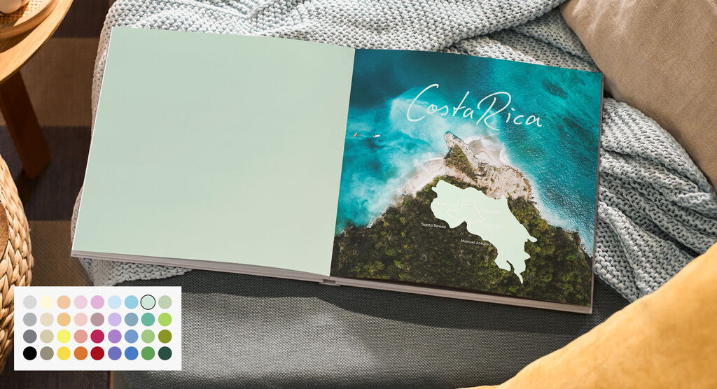 Offenes CEWE FOTOBUCH mit Luftaufnahme der Küste, Schriftzug Costa Rica, links farbige Einbandinnenseite, unten Farbauswahl