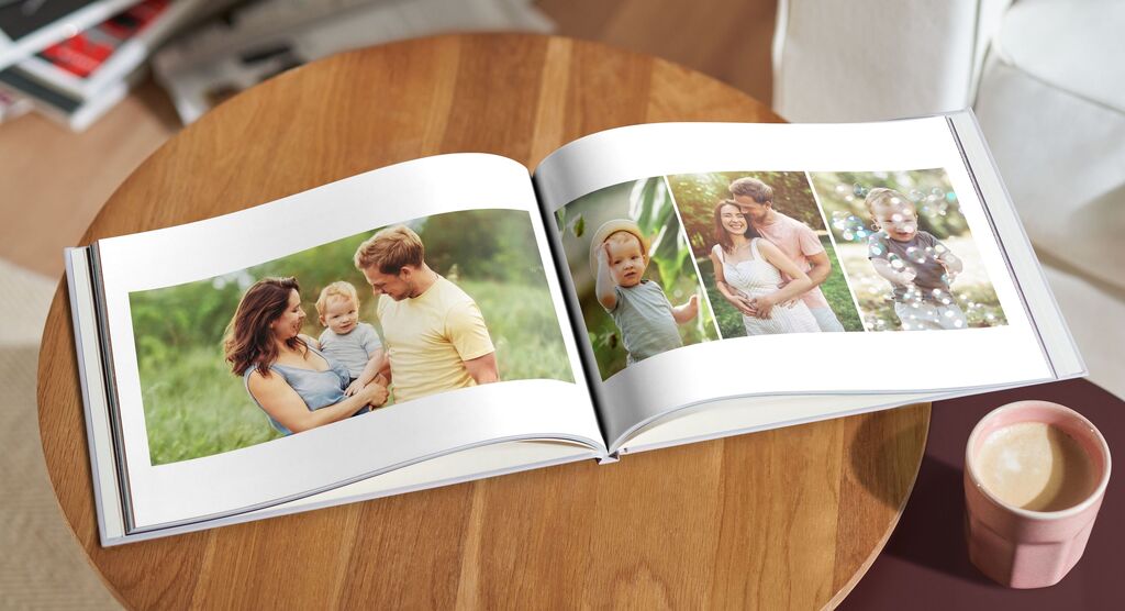 Ein offenes Fotobuch auf einem Tisch, mit Familienfotos und einem Kaffee daneben