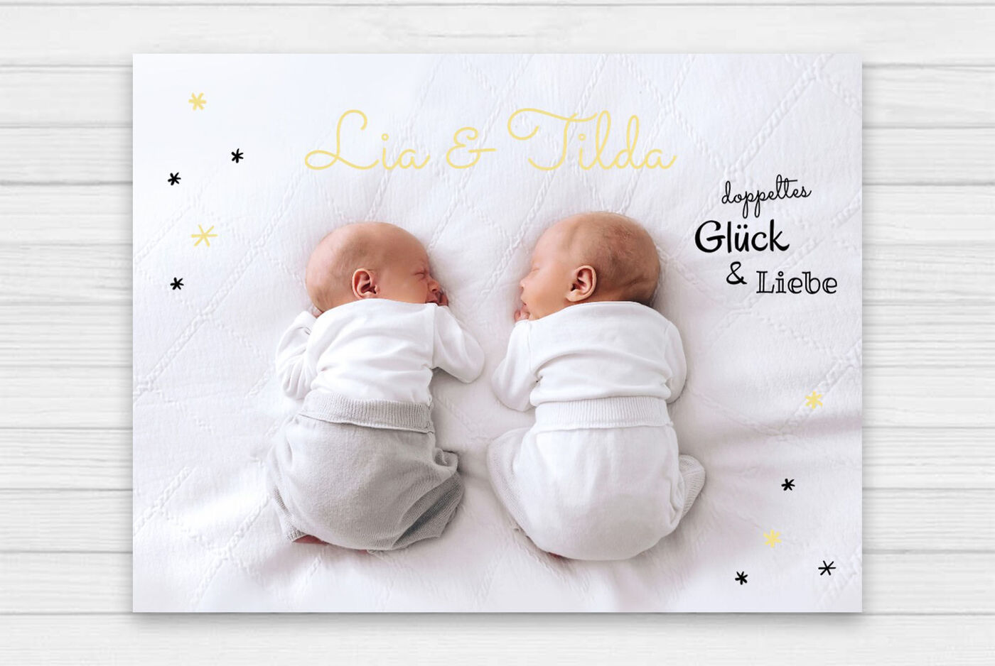 Zwei süße Babys in weißen Outfits liegen auf einer Decke. Sie erfreuen sich aneinander.
