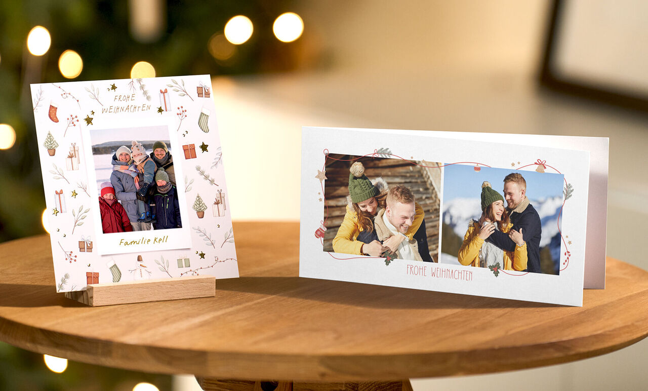 CEWE Grußkarten mit Familienfotos, links stehende Karte im Holzständer, rechts liegende Karte auf Tisch