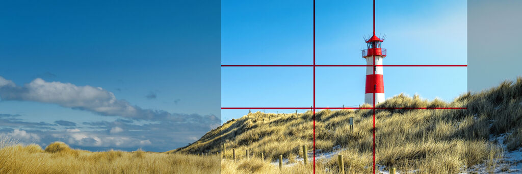 Roter Leuchtturm auf einer Dünenlandschaft unter blauem Himmel