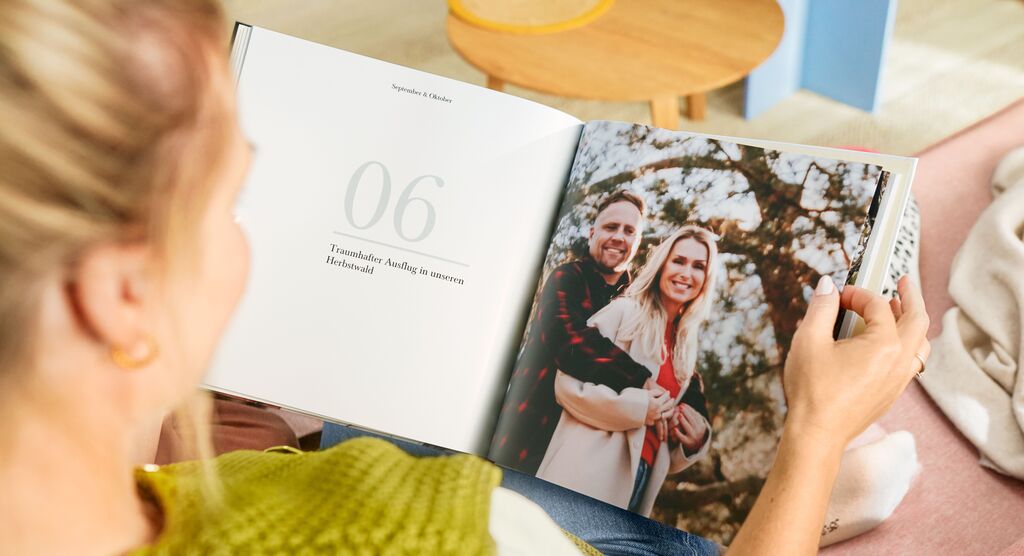Eine Person blättert durch ein Fotobuch mit einer Seite, die ein Paar in der Natur zeigt