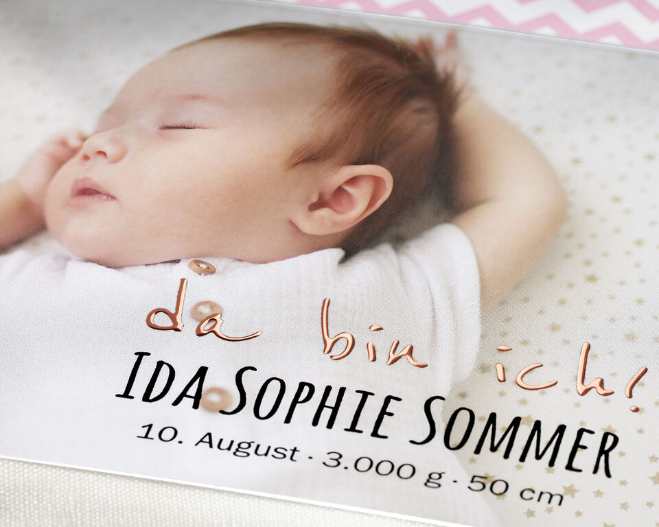 Ein niedliches Baby in einem weißen Oberteil liegt entspannt auf einem Kissen und schaut zur Seite.