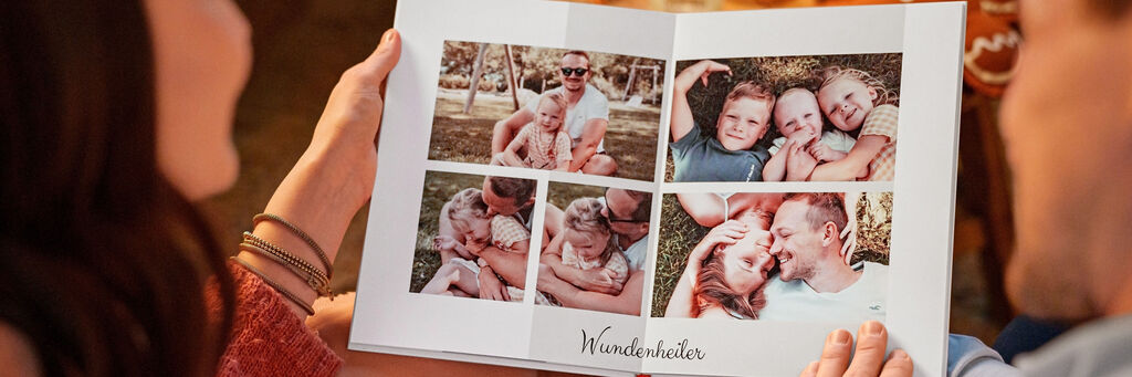 Eine Person hält ein offen gelegtes Fotobuch mit schönen Familienfotos. Der Titel des Buches ist "Wunderwelten".