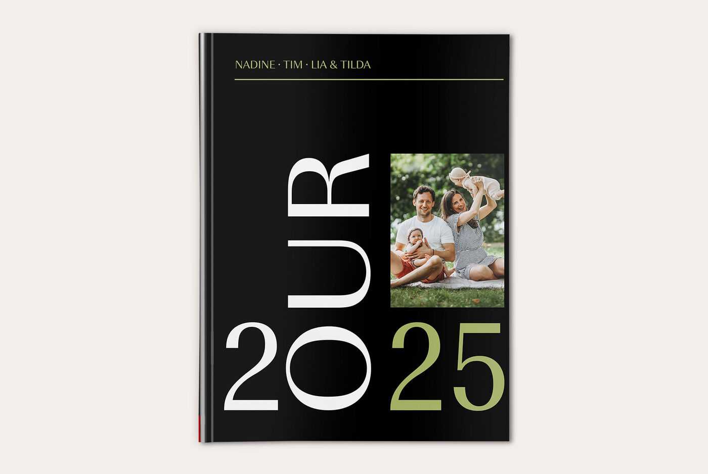 Schwarzes Fotobuch mit großen Ziffern und einem Familienfoto im Hintergrund