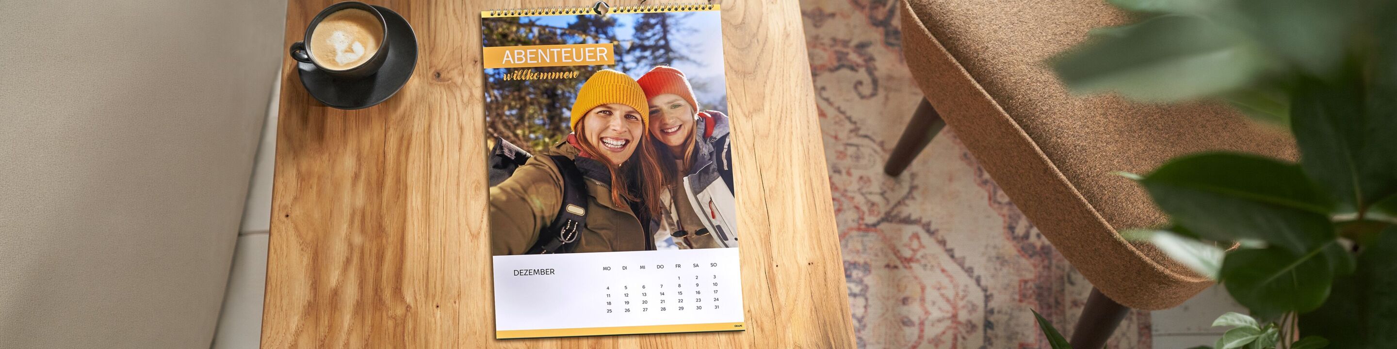 Kalender liegt auf Holztisch neben Kaffeetasse
