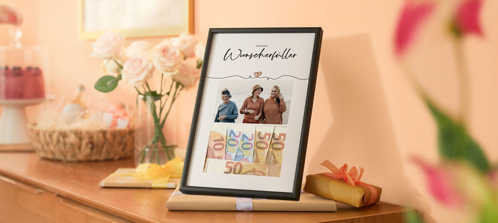 Schwarz gerahmtes Wunschbild mit Geldscheinen, daneben Geschenke und Rosen