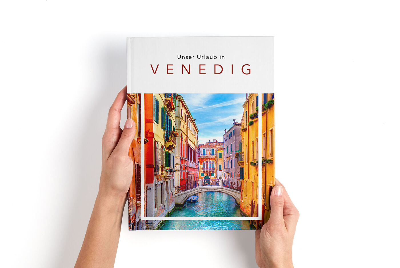 Ein geöffneter CEWE FOTOBUCH mit dem Titel "Unser Urlaub in Venedig" und einem schönen Kanalbild