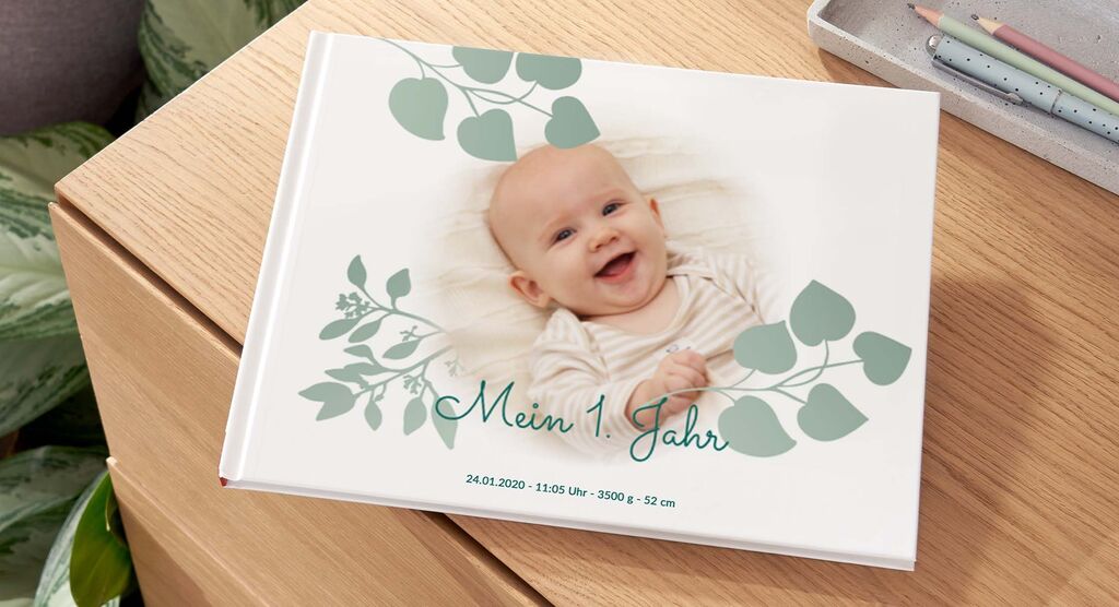 Ein CEWE FOTOBUCH mit dem Titel "Mein 1 Jahr" auf einem Holztisch.