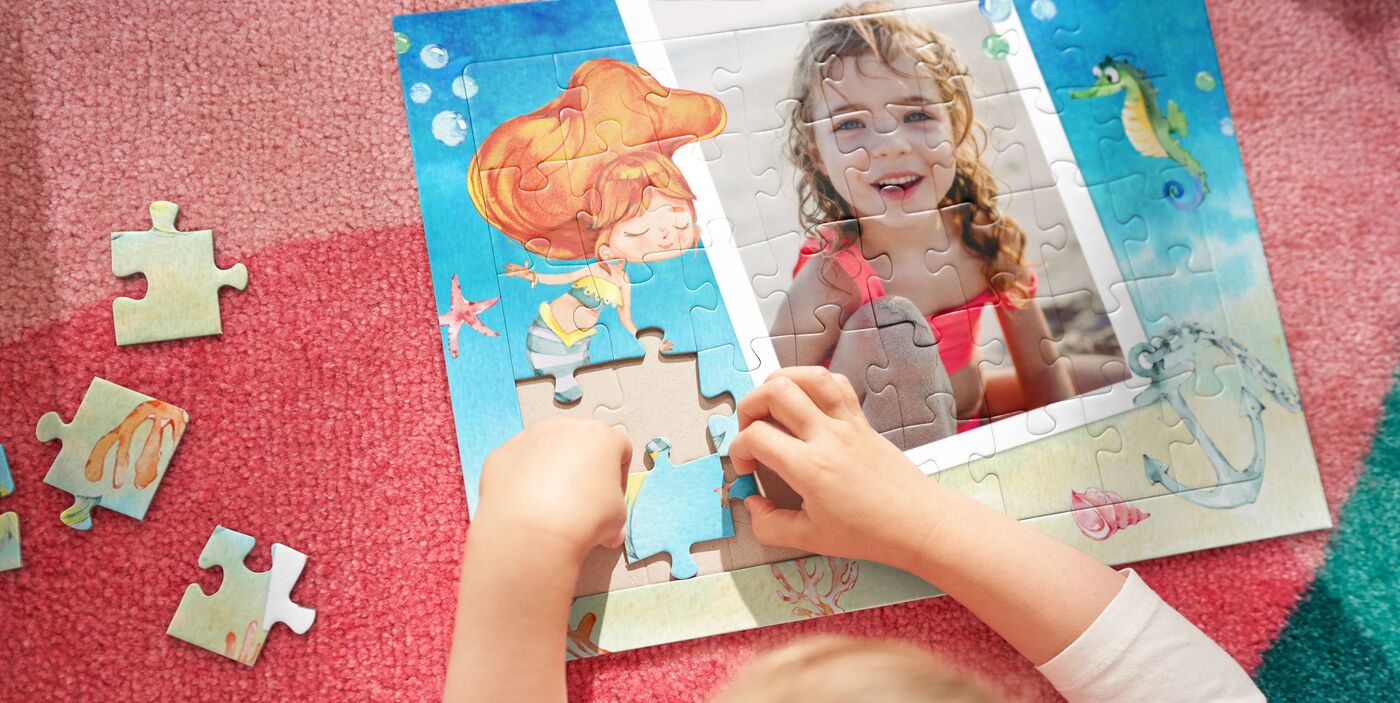 Kinderhände setzen liebevoll ein Puzzle mit einer Meerjungfrau und einem Foto zusammen