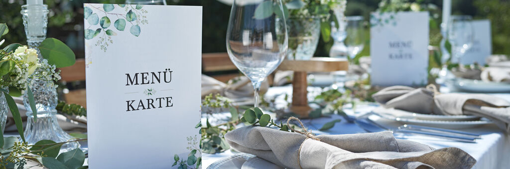 Elegante Dekoration einer Festtafel mit Menükarten und frischen Blumen.