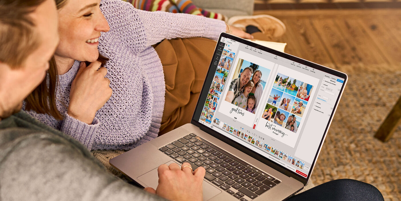 Ein Paar gestaltet gemeinsam ein CEWE FOTOBUCH am Laptop und freut sich über ihre Erinnerungen.