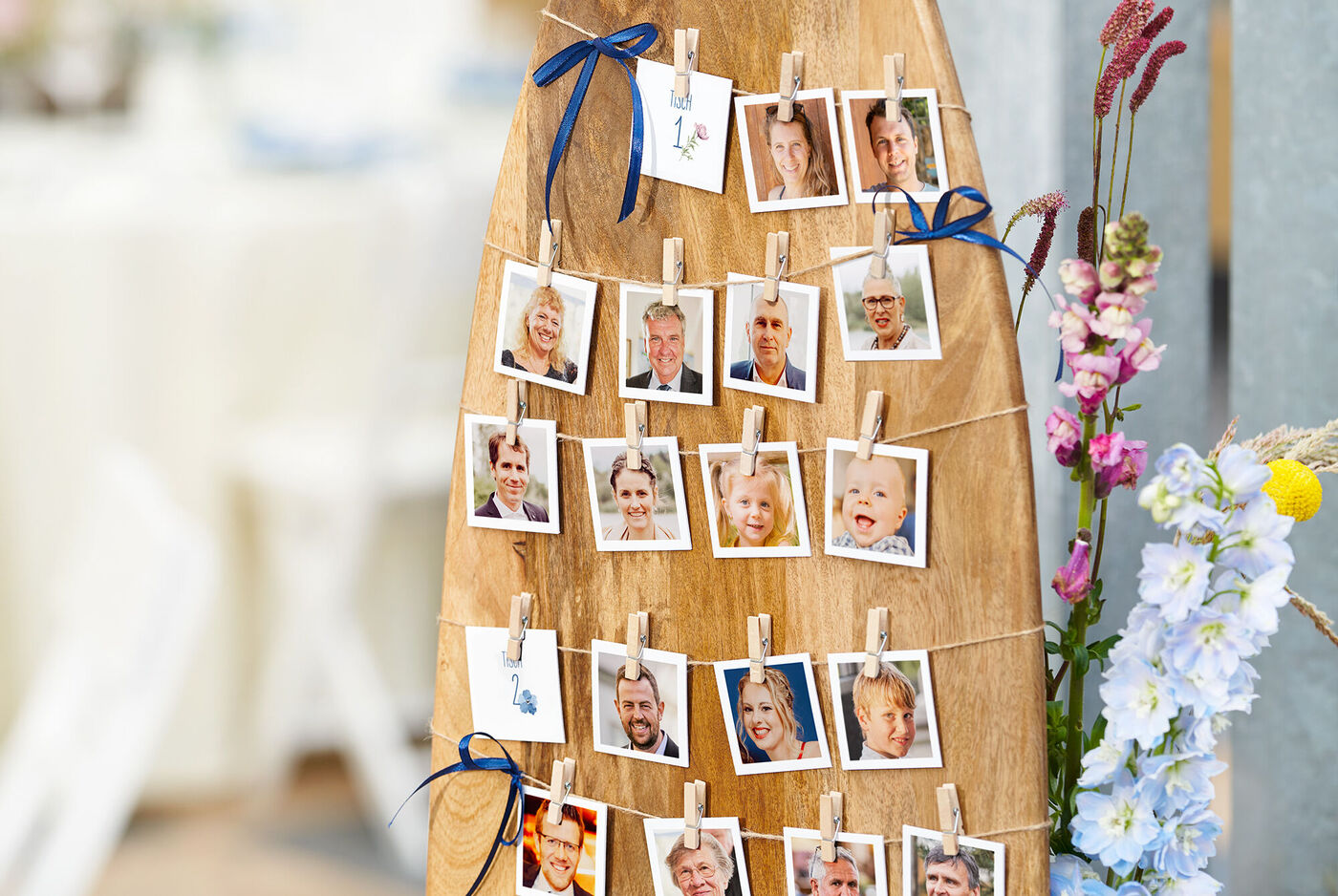 Ein rustikales Holzbrett mit vielen kleinen Fotos von Gästen, die mit Klammern befestigt sind