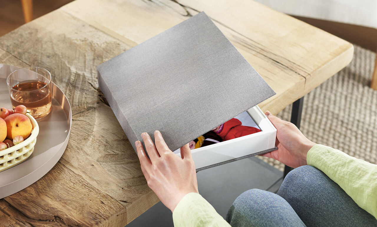Person öffnet edle Geschenkbox mit CEWE Fotobuch