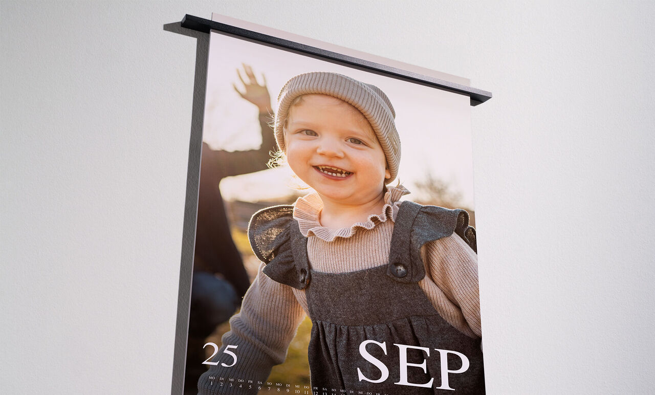 Ein liebevoll gestalteter Fotokalender mit einem Bild eines glücklichen Kindes im Freien, das in die Kamera lächelt und mit den Händen zeigt