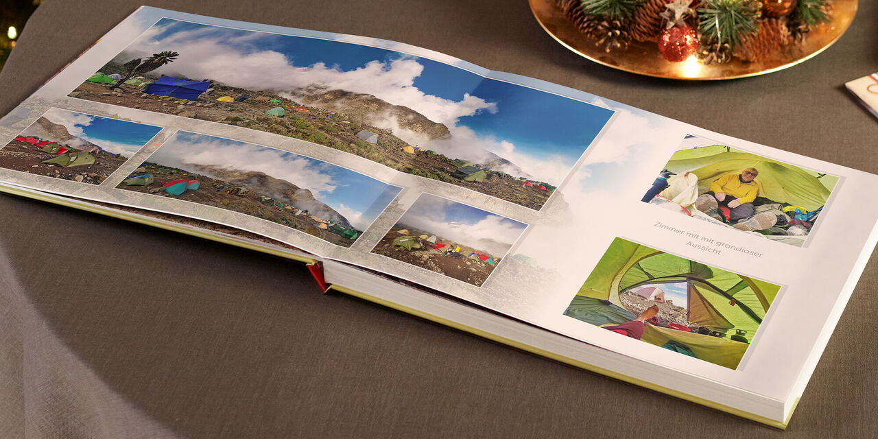 Geöffnetes CEWE Fotobuch mit bunten Erinnerungsfotos aus einem Campingurlaub.