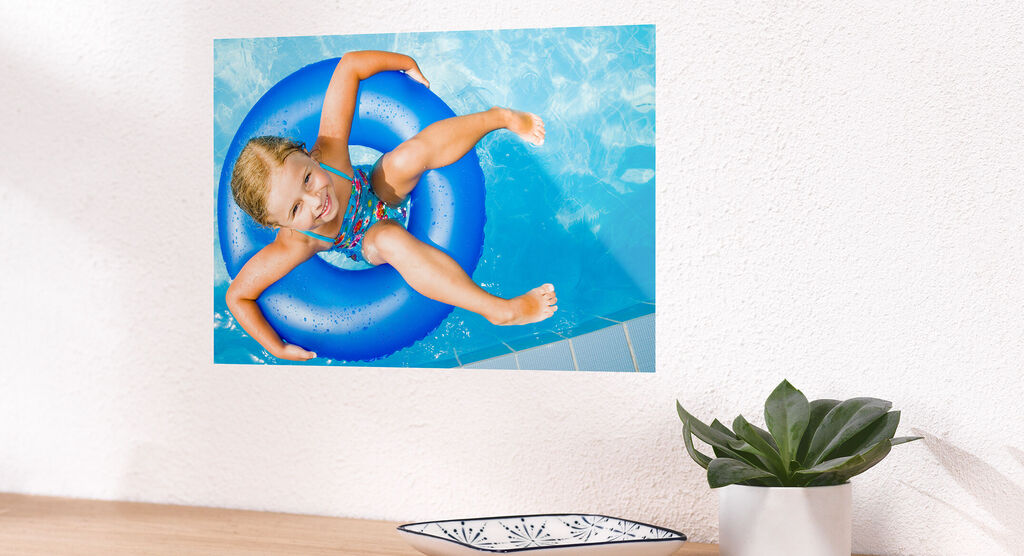 Ein fröhliches Mädchen sitzt in einem blauen Schwimmreifen im Wasser und genießt den Sommer.