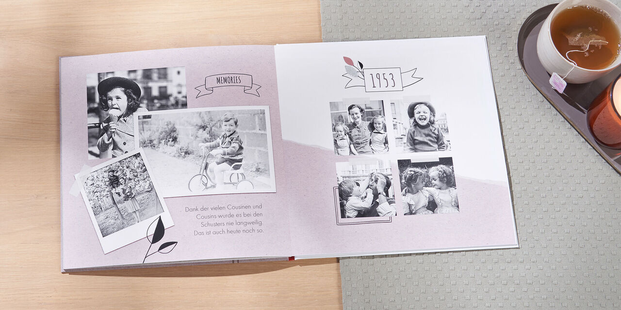 Ein geöffnetes Fotobuch mit nostalgischen Schwarz-Weiß-Fotos von Kindern, die auf einem Fahrrad fahren und in der Natur spielen