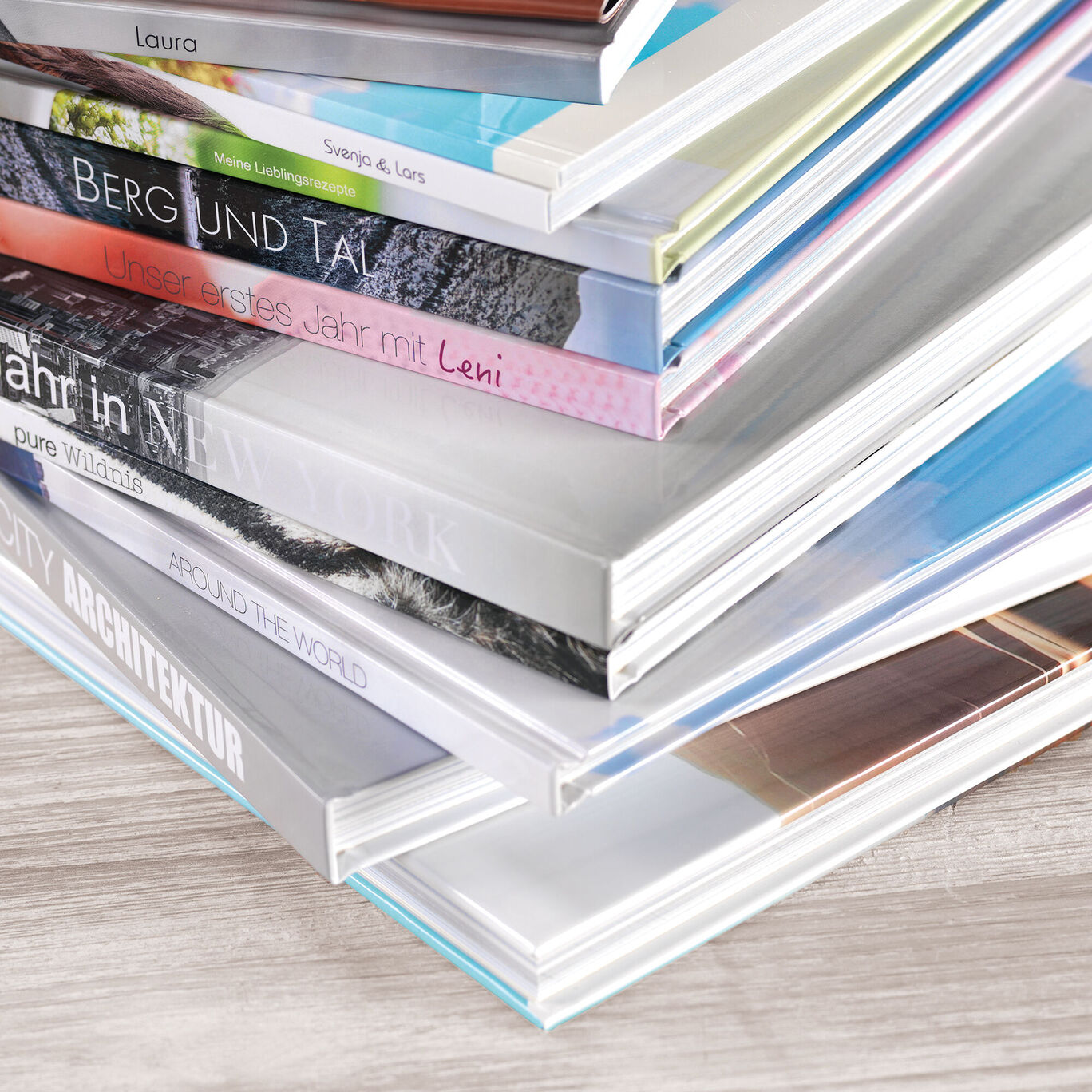 Eine stapelbare Sammlung von verschiedenen CEWE Fotobüchern, die farbenfroh gestaltet sind