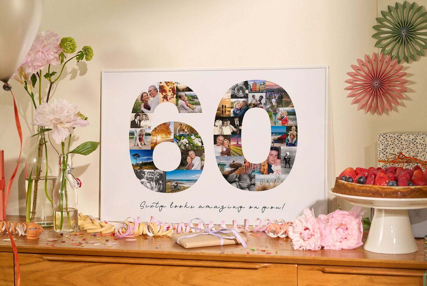 Foto-Collage in Form der Zahl 60 steht auf einer Kommode, Blumen und eine Torte zum Geburtstag als Dekoration