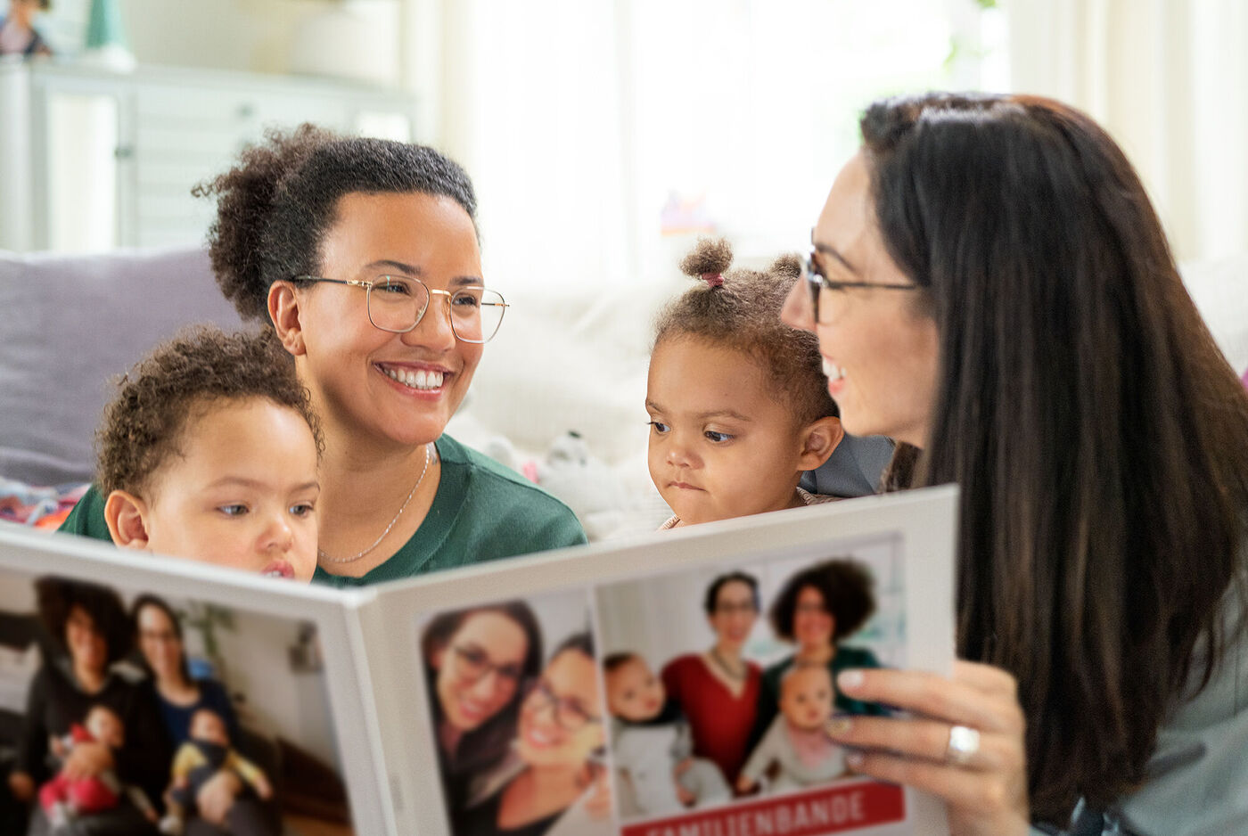 Eine Familie schaut mit Freude in ein Fotobuch voller Erinnerungen.