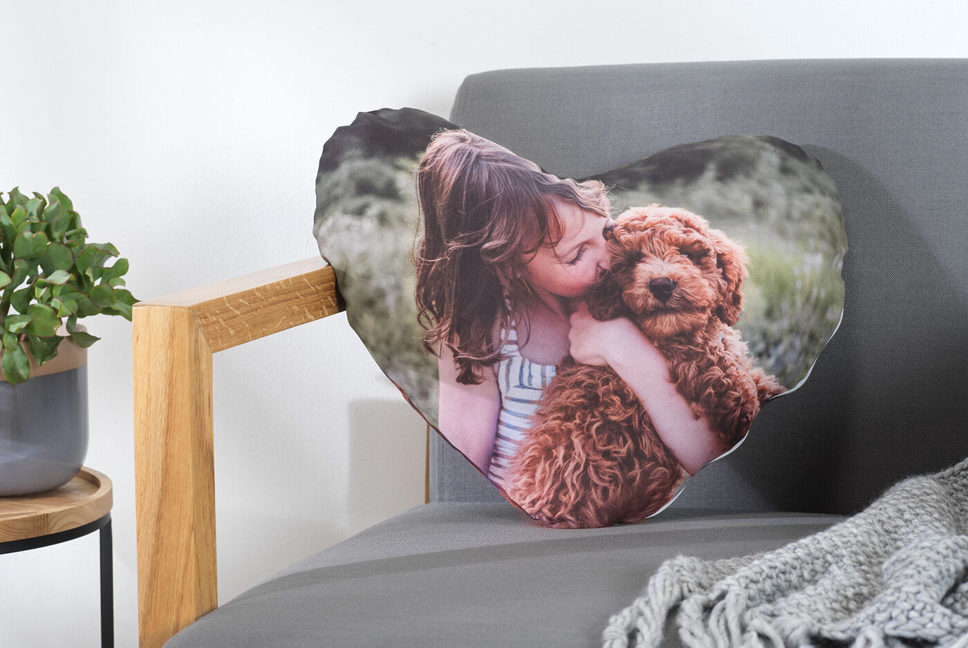 Ein Mädchen umarmt einen braunen Hund auf einem herzförmigen Kissen