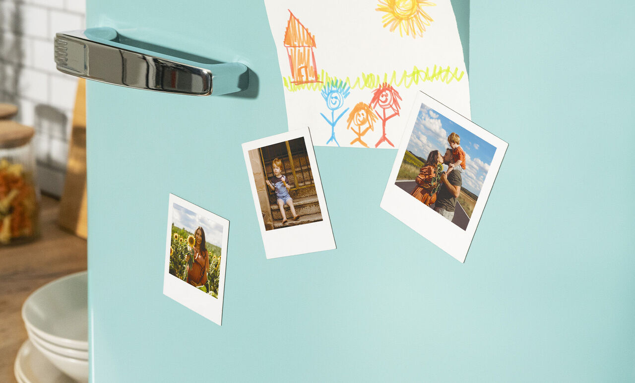 Drei kleine Fotos mit glücklichen Erinnerungen auf einem Kühlschrank haften.