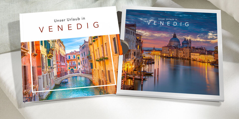 Zwei CEWE FOTOBUCH Exemplare mit Venedig-Fotos liegen auf einem hellen Sofa