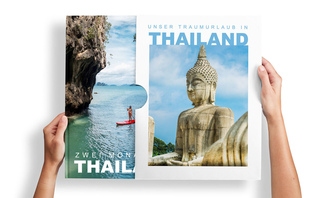 Person zieht ein CEWE FOTOBUCH Thailand mit Kajak- und Buddha-Motiv aus einem Schuber