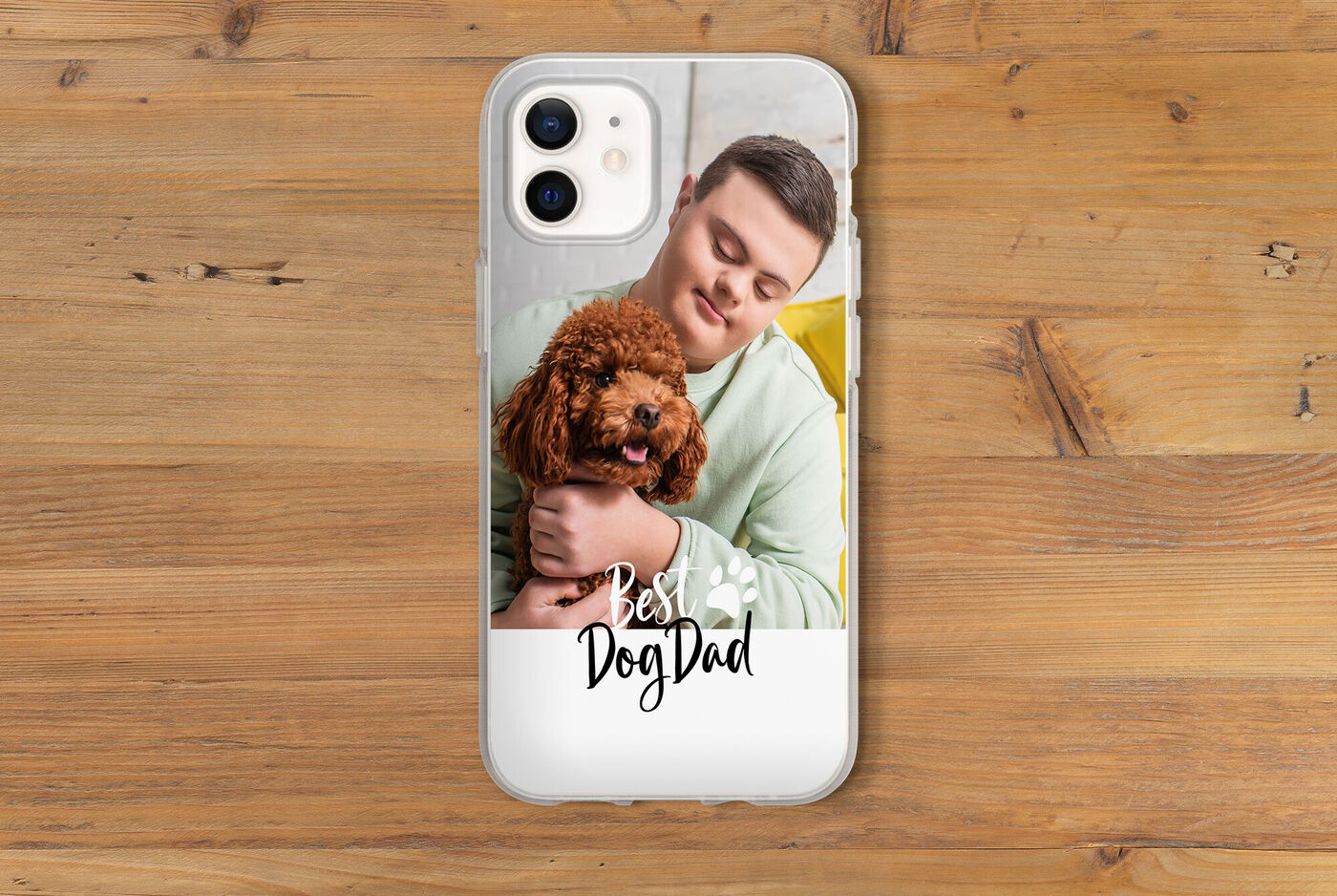 Ein Hundebesitzer hält seinen Hund sanft in den Armen, der Handyhülle ist das Wort "Best Dog Dad" aufgedruckt.