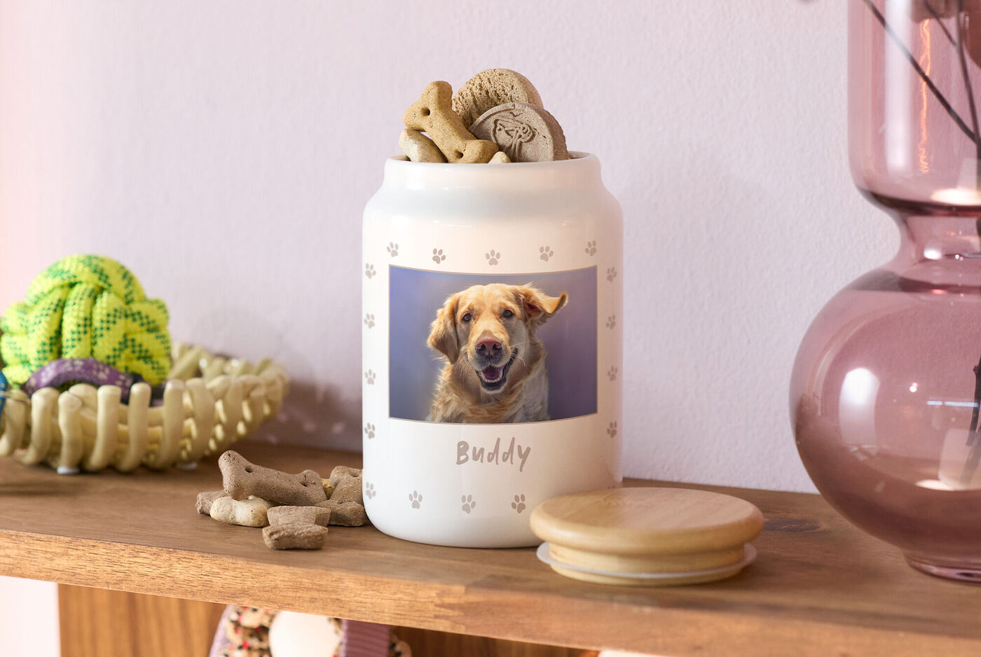 Leckerlidose mit Hundekeksen und Hundefoto, Name Buddy aufgedruckt, daneben Holzdeckel, auf einem Regal