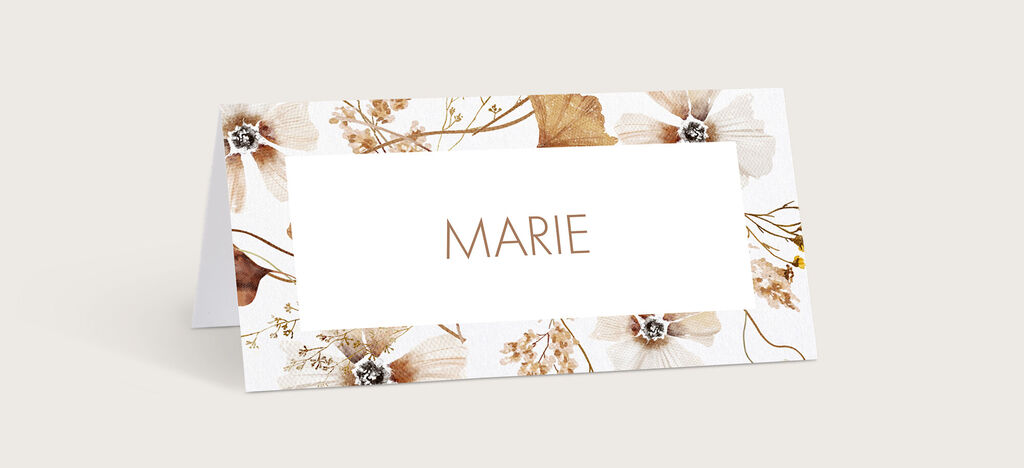 Eine elegante Platzkarte mit Blumenmuster und dem Namen Marie in goldener Schrift