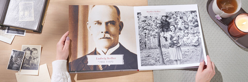 Ein geöffnetes Fotobuch mit historischen Bildern auf einem Tisch.