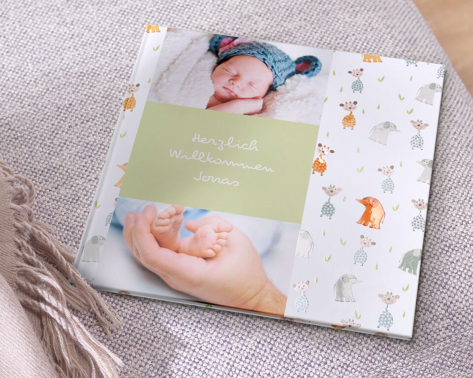 Ein liebevolles Fotobuch mit süßem Tierdesign. Auf der Vorderseite steht "Herzlich Willkommen Jonas" und zeigt die Hände eines Erwachsenen, die ein Baby halten