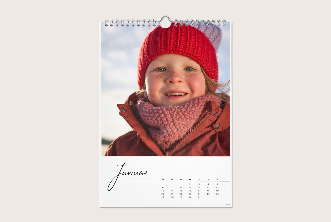 Eine Person trägt eine rote Mütze und einen warmen Schal, die einen Jahreskalender für Januar präsentiert