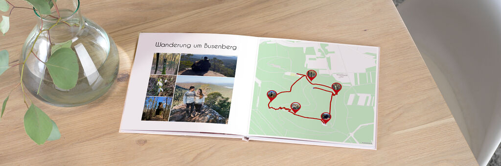 Ein offenes CEWE FOTOBUCH auf einem Tisch, mit Bildern von einer Wanderung und einer Karte.