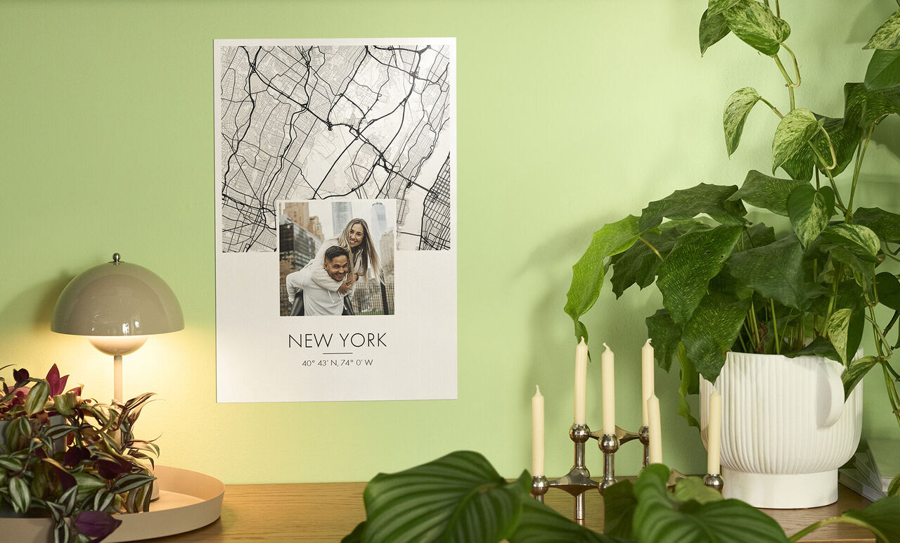 Ein Poster von New York hängt an einer grünen Wand. Es zeigt ein Szenenbild und den Schriftzug "NEW YORK".