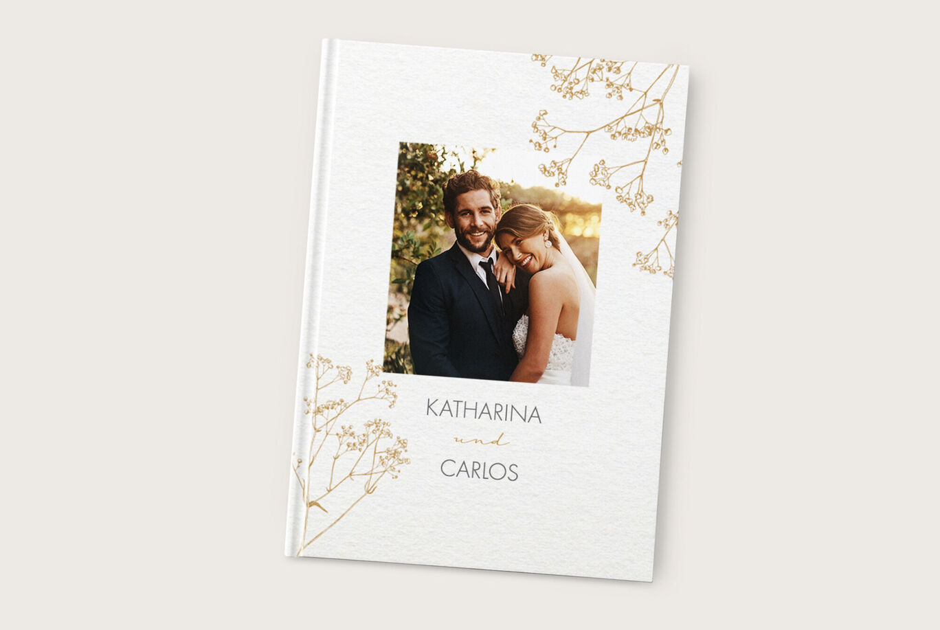 Elegantes Hochzeitsfotobuch mit einem Pärchen im Vordergrund und zarten Blumenelementen.