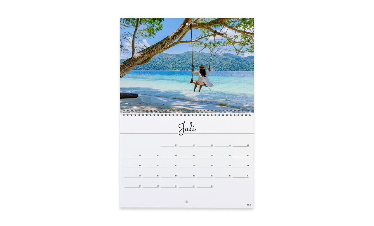 Ein Kind schwingt fröhlich auf einer Hängematte unter einem Baum am Strand, umgeben von blauem Wasser. CEWE Fotokalender