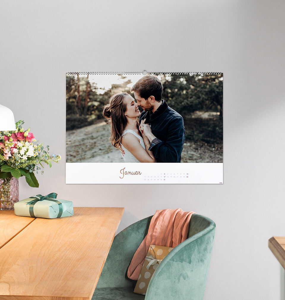 Ein romantischer Kalender zeigt einen glücklichen Kuss zwischen zwei Personen. Im Hintergrund sind Blumen und eine grüne Umgebung sichtbar. Der Monatsname Januar steht unten im Bild.