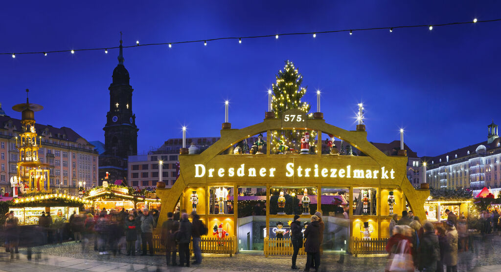 Der Dresdner Striezelmarkt bei Nacht mit festlich beleuchteter Brücke und vielen Besuchern